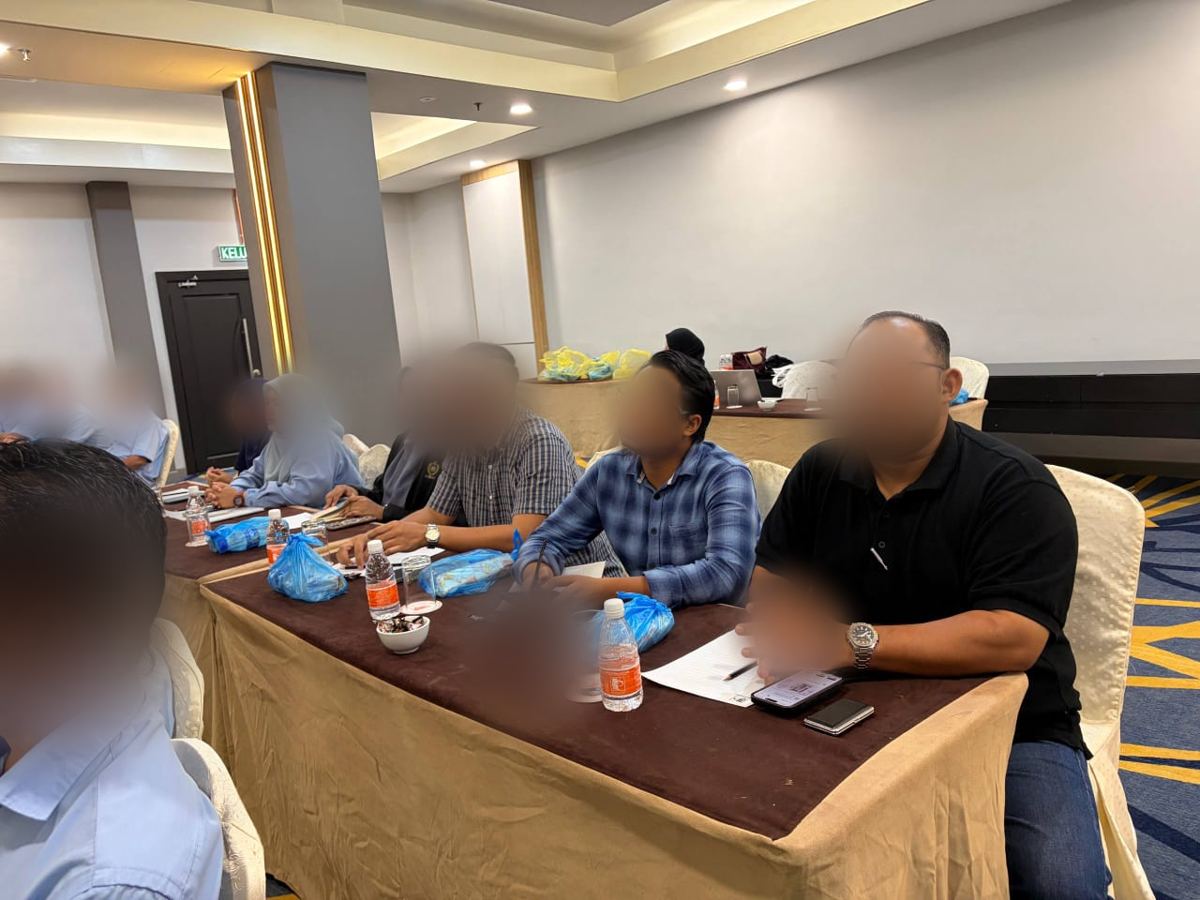 Participants seated at tables during a training session in a hall